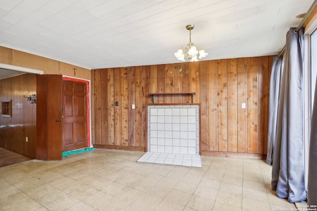 spare room featuring a chandelier and wood walls