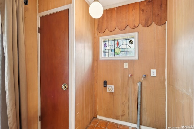 laundry area featuring tile patterned floors and wood walls