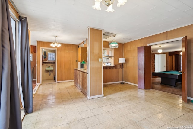 kitchen featuring a chandelier, billiards, hanging light fixtures, and wood walls