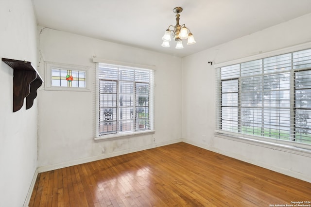 unfurnished room with hardwood / wood-style flooring and a notable chandelier