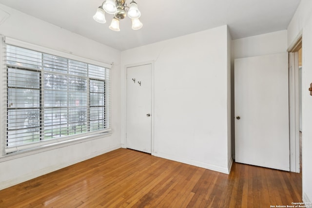 unfurnished bedroom featuring hardwood / wood-style floors, a closet, and a notable chandelier