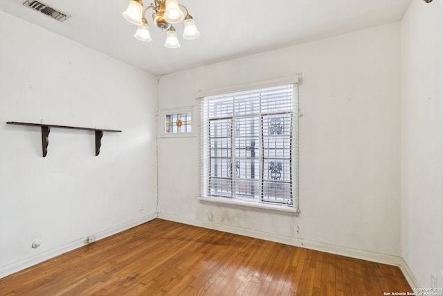 unfurnished room with wood-type flooring and an inviting chandelier