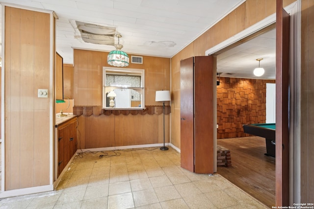 kitchen featuring billiards, hanging light fixtures, and wooden walls