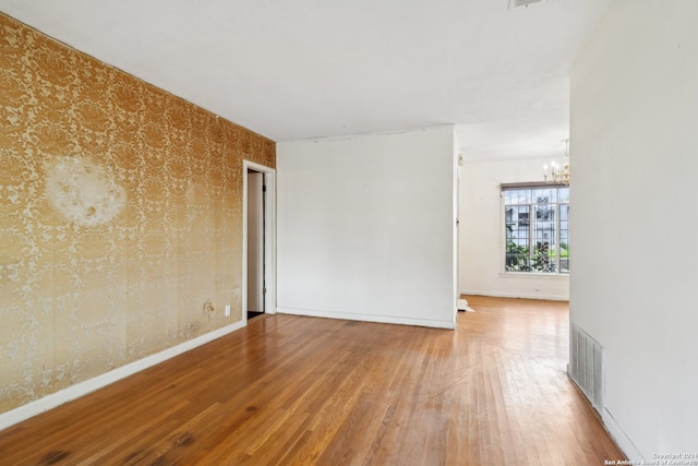 spare room featuring a chandelier and wood-type flooring