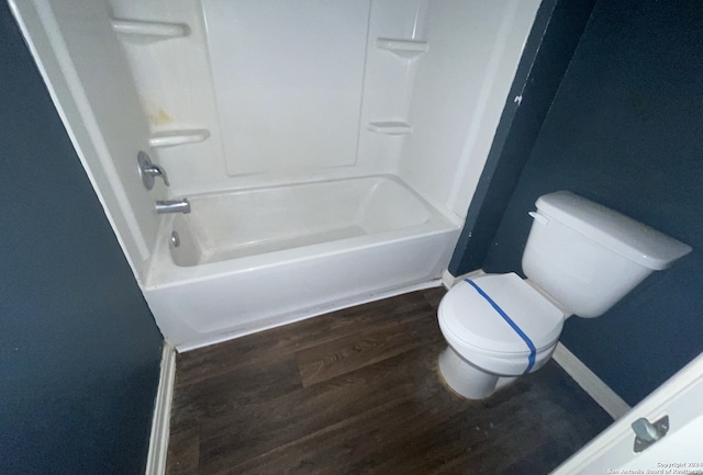 bathroom with hardwood / wood-style flooring,  shower combination, and toilet