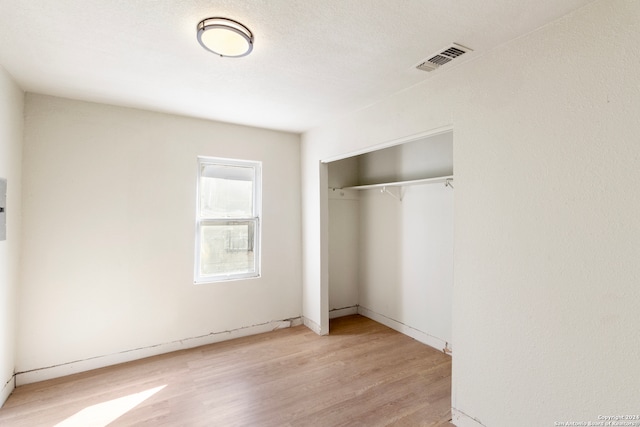 unfurnished bedroom featuring light wood-type flooring, a textured ceiling, and a closet