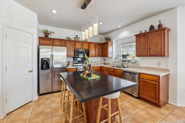 kitchen featuring stainless steel appliances, sink, decorative light fixtures, a kitchen island, and a breakfast bar area