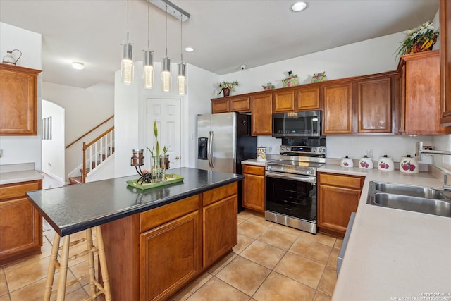 kitchen with pendant lighting, light tile patterned flooring, appliances with stainless steel finishes, a kitchen island, and a breakfast bar area