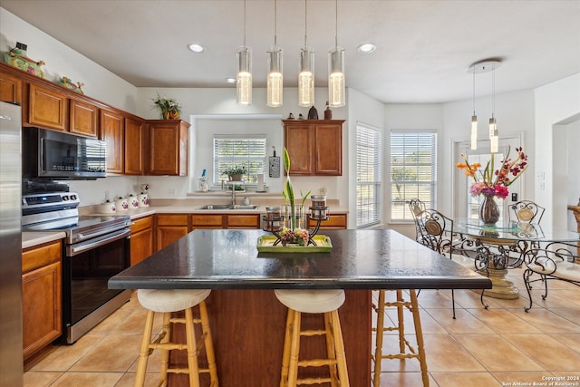 kitchen featuring a kitchen breakfast bar, a center island, stainless steel appliances, and sink