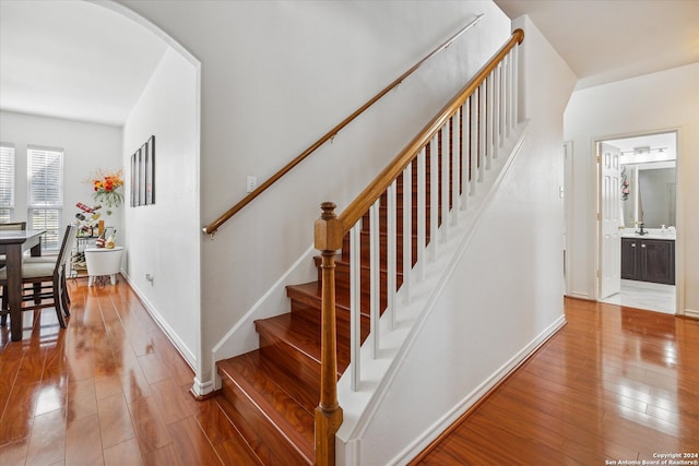 staircase with hardwood / wood-style floors and sink