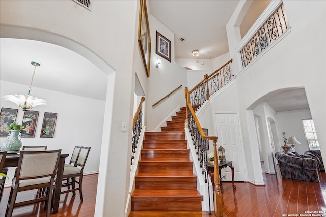 stairway featuring a chandelier, a high ceiling, and hardwood / wood-style flooring