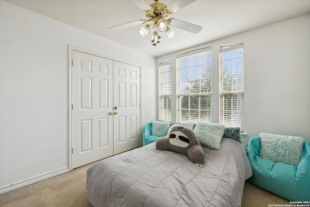 bedroom with ceiling fan, light carpet, and a closet