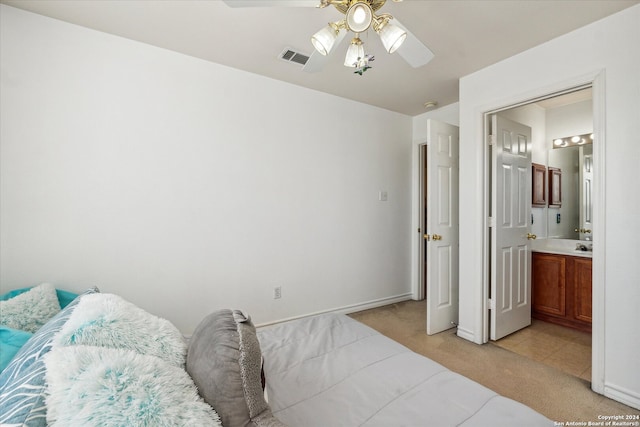 bedroom with ceiling fan, ensuite bathroom, and light carpet