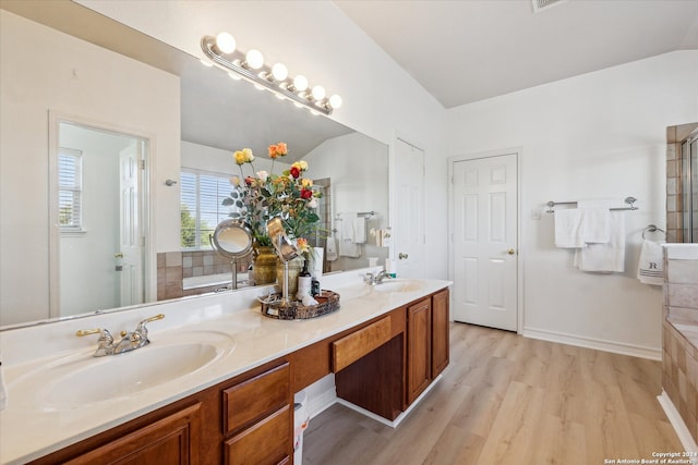 bathroom featuring a tub, hardwood / wood-style floors, vanity, and lofted ceiling