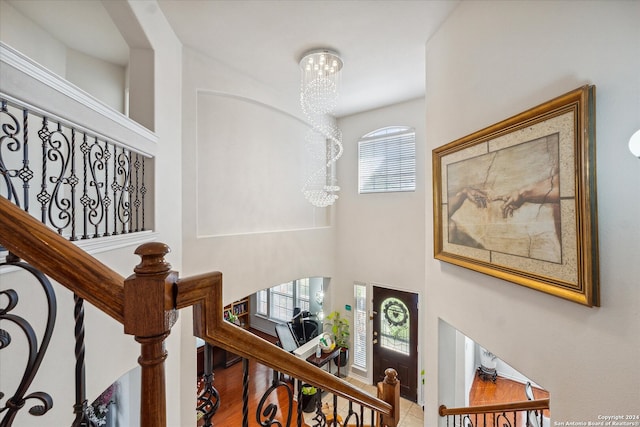 stairway featuring wood-type flooring, an inviting chandelier, and a wealth of natural light