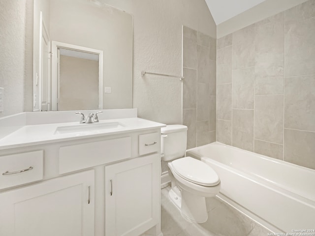 full bathroom featuring tiled shower / bath, vanity, vaulted ceiling, and toilet