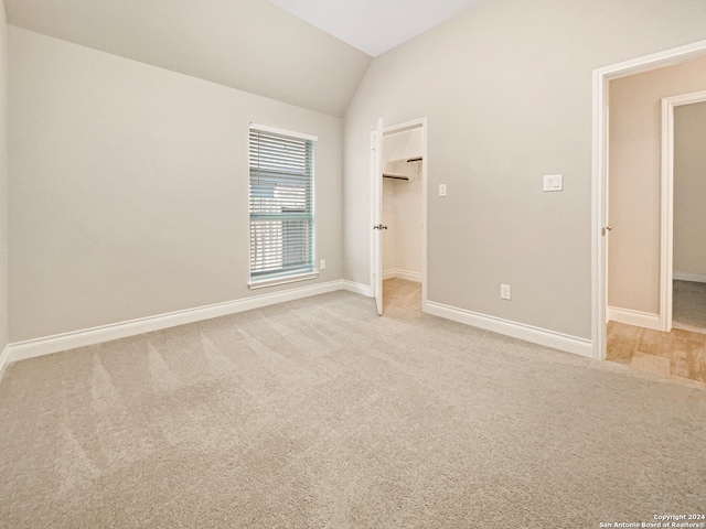 carpeted spare room with lofted ceiling