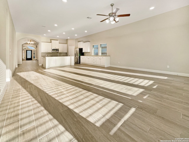 unfurnished living room featuring ceiling fan and light wood-type flooring