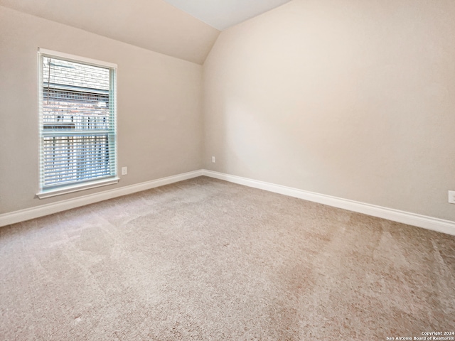 carpeted spare room with lofted ceiling