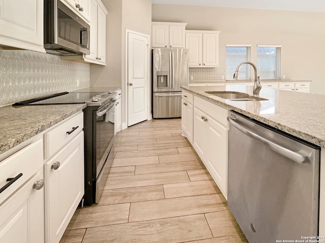 kitchen with sink, white cabinets, light hardwood / wood-style flooring, and appliances with stainless steel finishes