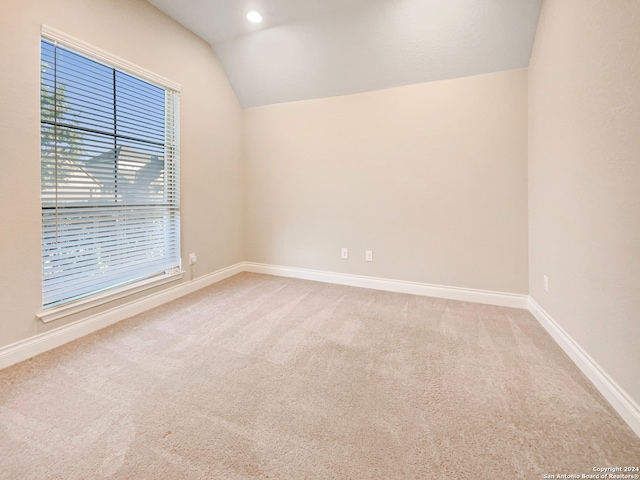 carpeted empty room featuring lofted ceiling