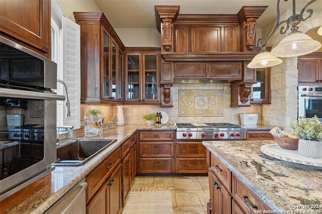 kitchen featuring backsplash, light stone counters, hanging light fixtures, and appliances with stainless steel finishes