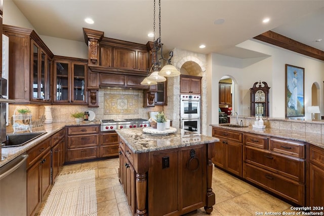 kitchen with a center island, stainless steel appliances, hanging light fixtures, tasteful backsplash, and light stone counters