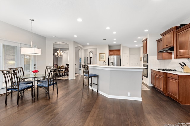 kitchen with stainless steel appliances, dark hardwood / wood-style flooring, a notable chandelier, a spacious island, and decorative light fixtures