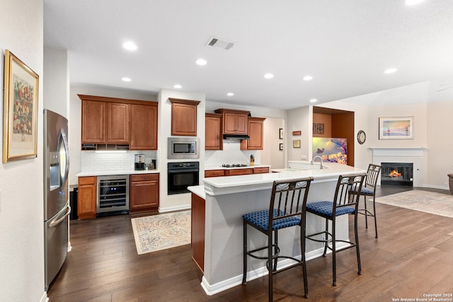 kitchen featuring a center island, dark wood-type flooring, wine cooler, appliances with stainless steel finishes, and a kitchen bar