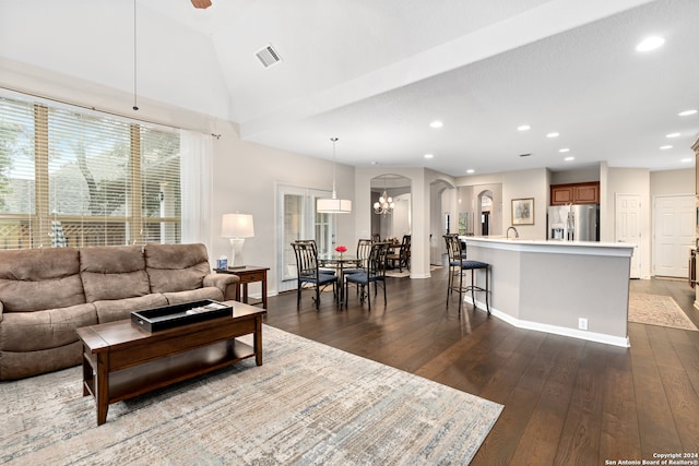 living room featuring ceiling fan with notable chandelier, lofted ceiling, and dark wood-type flooring