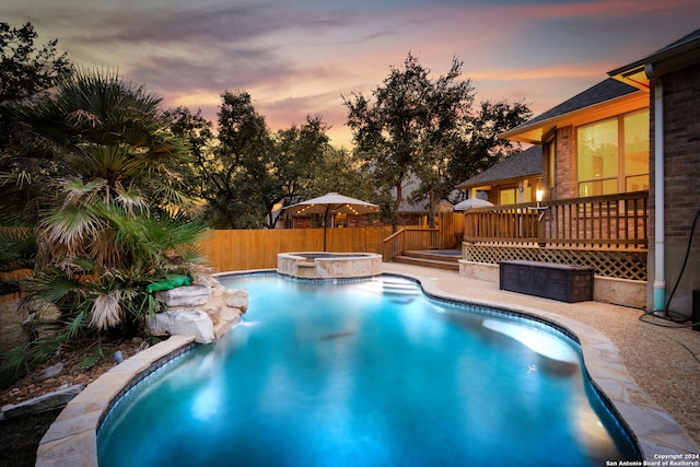 pool at dusk featuring an in ground hot tub and a wooden deck