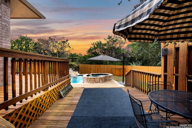 deck at dusk with a pool with hot tub