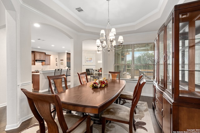 dining space featuring a raised ceiling, crown molding, a chandelier, and light hardwood / wood-style floors