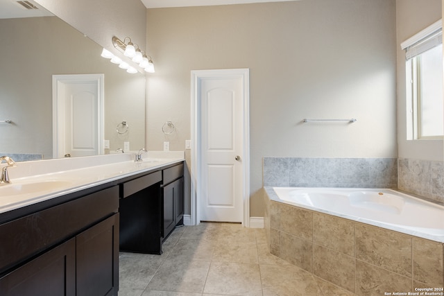 bathroom featuring tile patterned floors, a relaxing tiled tub, and vanity