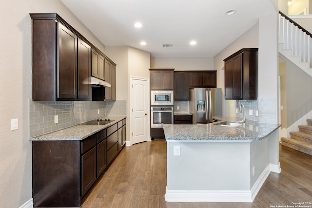 kitchen with light stone countertops, sink, light hardwood / wood-style floors, and appliances with stainless steel finishes