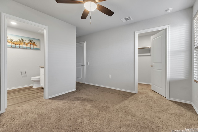 unfurnished bedroom with ceiling fan, connected bathroom, light carpet, a walk in closet, and a closet