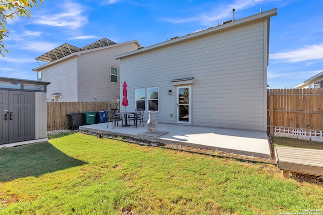 rear view of property with a storage shed, a patio, and a lawn