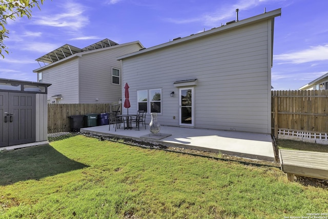 back of property featuring a shed, a yard, and a patio area