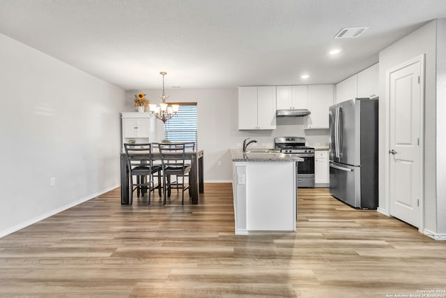 kitchen with white cabinetry, a center island with sink, dark stone counters, pendant lighting, and stainless steel appliances