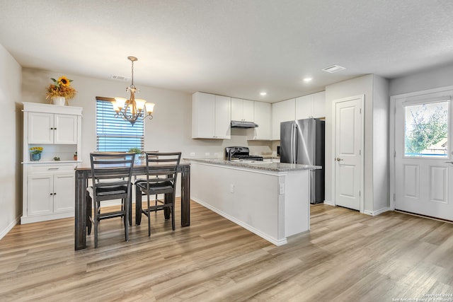 kitchen with white cabinetry, range, hanging light fixtures, stainless steel refrigerator, and light hardwood / wood-style floors