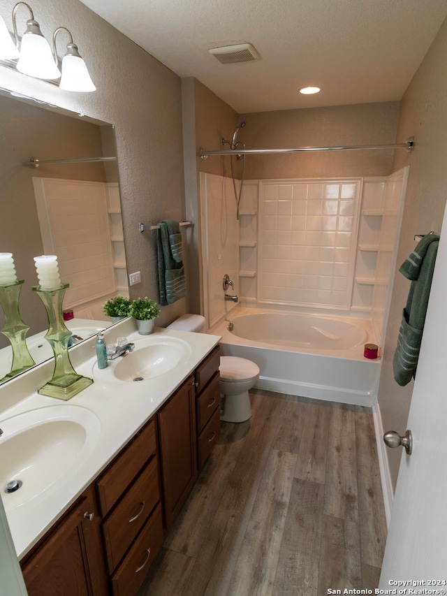 full bathroom featuring vanity, a textured ceiling, shower / washtub combination, hardwood / wood-style floors, and toilet