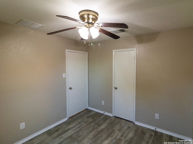 unfurnished bedroom with a textured ceiling, ceiling fan, and dark wood-type flooring