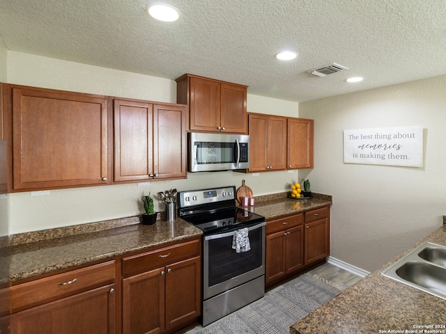 kitchen with sink, stainless steel appliances, a textured ceiling, and wood-type flooring