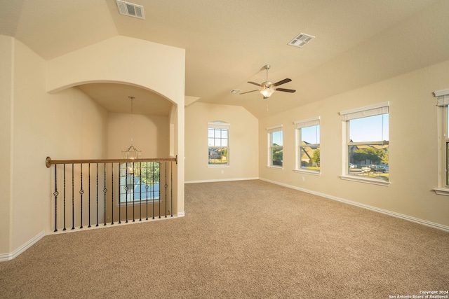 carpeted spare room featuring ceiling fan with notable chandelier and vaulted ceiling