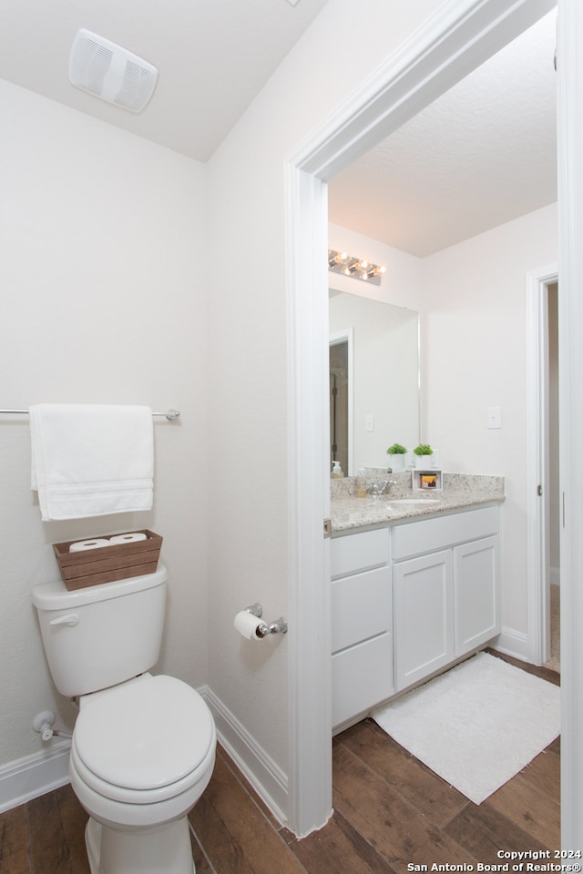 bathroom with toilet, vanity, and hardwood / wood-style flooring