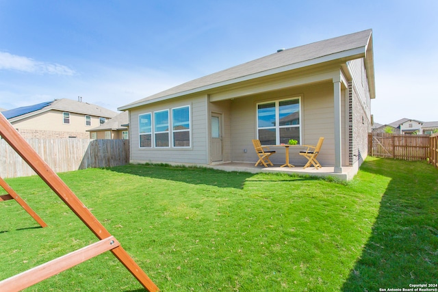 back of property with a yard and a patio area