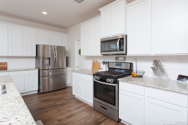 kitchen featuring decorative backsplash, white cabinetry, stainless steel appliances, and dark hardwood / wood-style floors