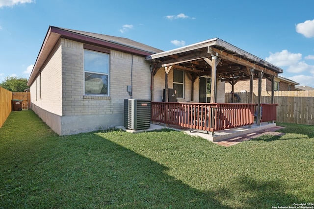 rear view of house featuring a yard, central AC unit, and a deck