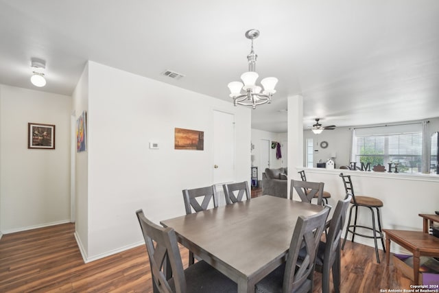 dining room with ceiling fan with notable chandelier and dark hardwood / wood-style flooring