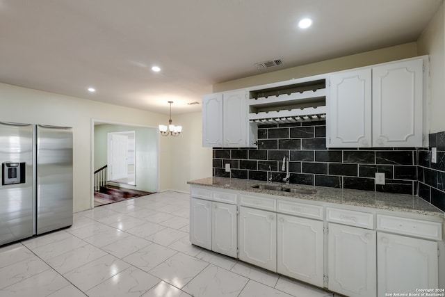 kitchen featuring backsplash, sink, stainless steel fridge with ice dispenser, decorative light fixtures, and white cabinetry